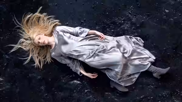 Yvaine lies in a silver dress on dark, rocky ground