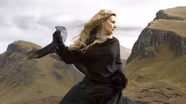 Yvaine runs across a windswept mountain valley in a flowing black dress