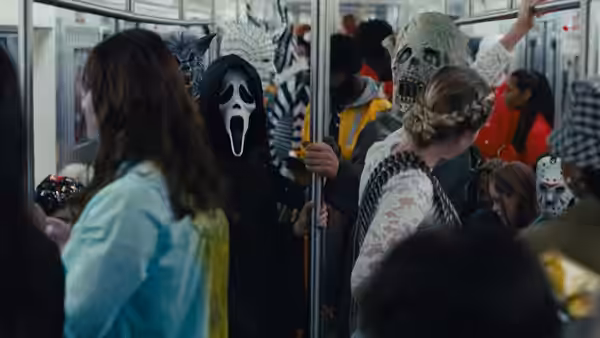 Ghostface standing among costumed passengers on a crowded subway train