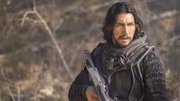 Mills (Adam Driver) holds a rifle while wearing armor outdoors