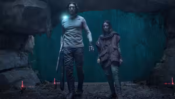 Mills (Adam Driver) holds a glowing device while Koa (Ariana Greenblatt) stands nearby in a cave