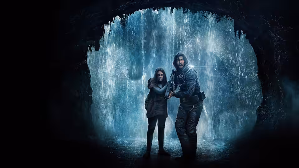 Mills (Adam Driver) and Koa (Ariana Greenblatt) stand together in a cave with falling water