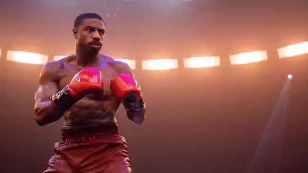 Adonis Creed (Michael B. Jordan) standing with red gloves raised