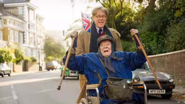 Miss Shepherd (Maggie Smith) rides in a wheelchair as Alan Bennett (Alex Jennings) walks behind her