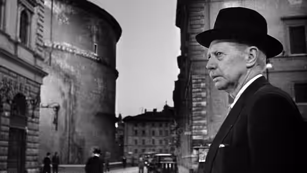 Umberto Domenico Ferrari (Carlo Battisti) standing on a city street in a bowler hat