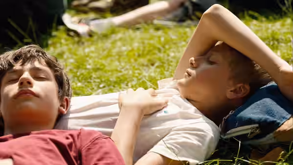 Léo (Eden Dambrine) and Rémi (Gustav De Waele) lying side by side on grass