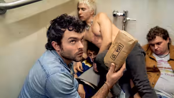 A man holding a paper bag in a bathroom with three others nearby