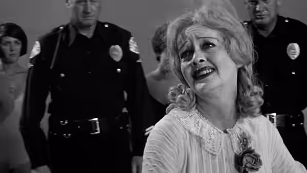 Baby Jane Hudson (Bette Davis) looks distressed as police officers stand behind her