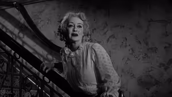 Baby Jane Hudson (Bette Davis) pauses on a staircase