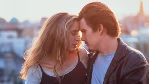 Céline (Julie Delpy) and Jesse (Ethan Hawke) standing close with foreheads nearly touching on a rooftop