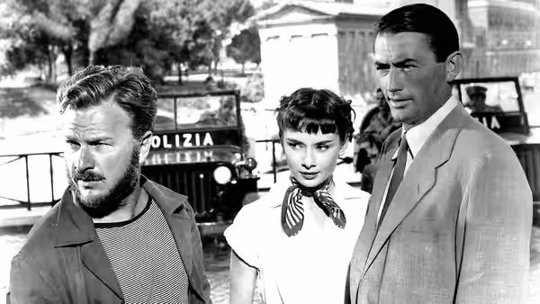 Irving Radovich (Eddie Albert) with Princess Ann (Audrey Hepburn) and Joe Bradley (Gregory Peck) by police vehicles