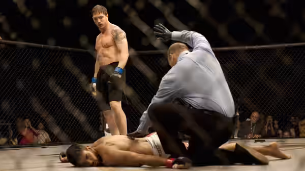Tommy Conlon (Tom Hardy) stands over opponent in an MMA cage