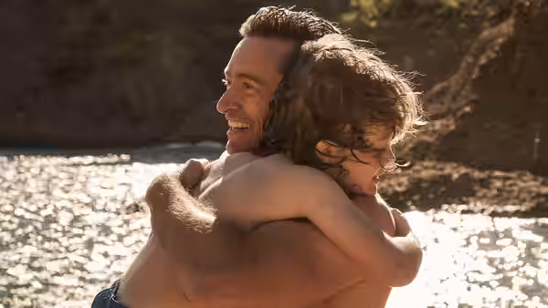 Peter (Hugh Jackman) hugging Nicholas (Zen McGrath) shirtless by sunlit water