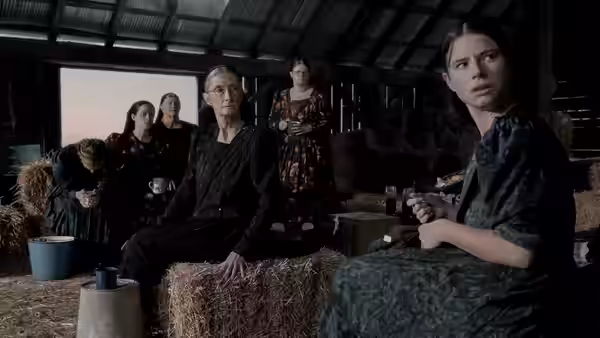 a man and several women sitting together in a large barn
