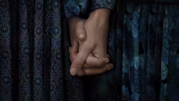 two hands clasped together on a patterned blue and green dress