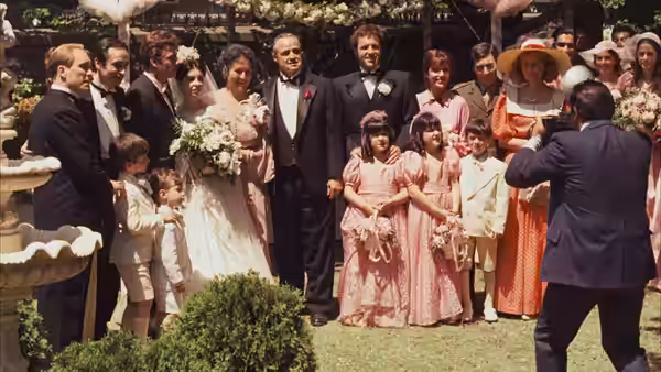 Don Vito Corleone (Marlon Brando) stands with bride and family at outdoor wedding