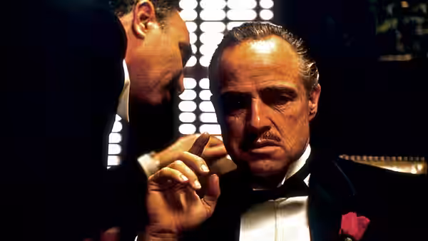Don Vito Corleone (Marlon Brando) listens to a man in a dark room