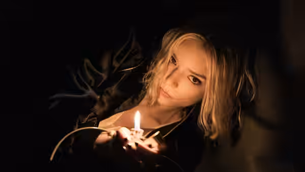 Lucky (Anya Taylor-Joy) holding a lit match in darkness