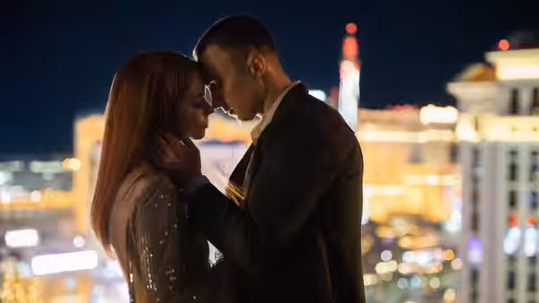 a couple embracing closely against a backdrop of city lights at night