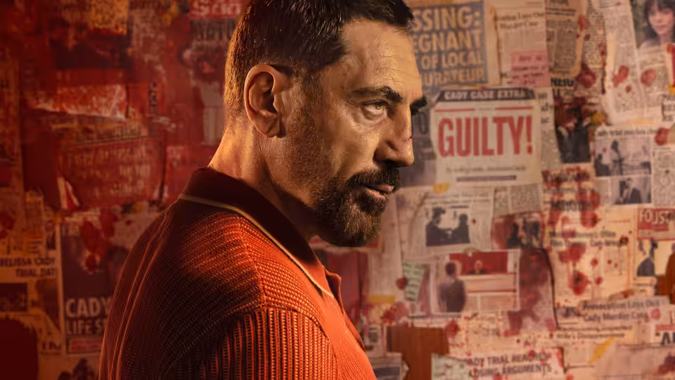 Max Cady (Javier Bardem) stands before a wall of newspaper clippings