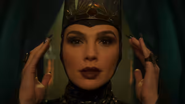 Gal Gadot as the Evil Queen raises her hands beside her face with long nails