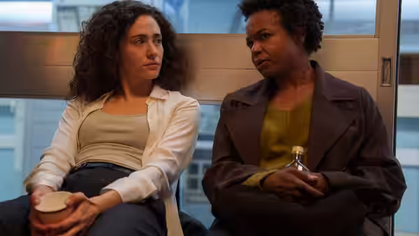 Alice Black (Emmy Rossum) and Nora Washington (Quincy Tyler Bernstine) sit side by side holding cups