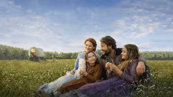 A man and woman sit with three children in a field