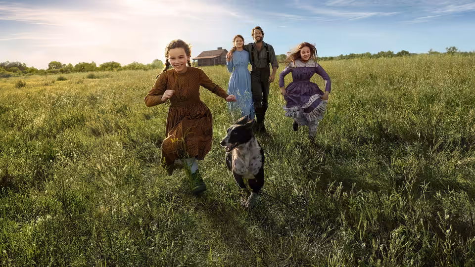A family and dog run across a wide green meadow