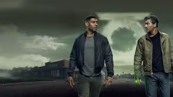 John Stewart (Aaron Pierre) and Hal Jordan (Kyle Chandler) stand in a barren field under dark clouds