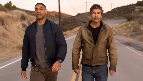 John Stewart (Aaron Pierre) and Hal Jordan (Kyle Chandler) walk along an empty road at dusk