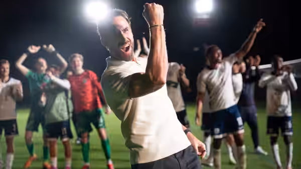 Joseph Fiennes as Gareth Southgate raising his arms in celebration on the pitch
