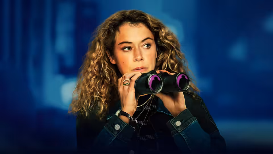 Paula Sanders (Tatiana Maslany) peering through binoculars at night