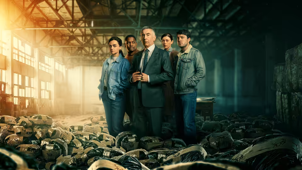 Don (Steve Coogan) stands with four others amid tires in a vast warehouse