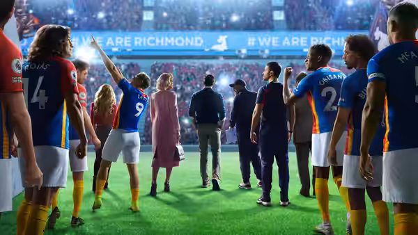 Players and staff gathered on the pitch with a crowd in the stands