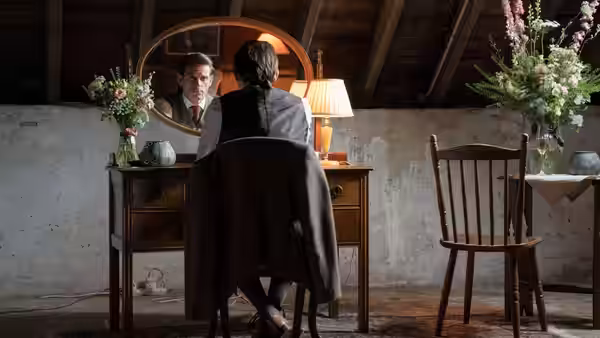 Niall sits at a wooden vanity table viewed from behind