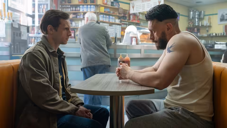 Niall and Ruben sit facing each other at a cafe table