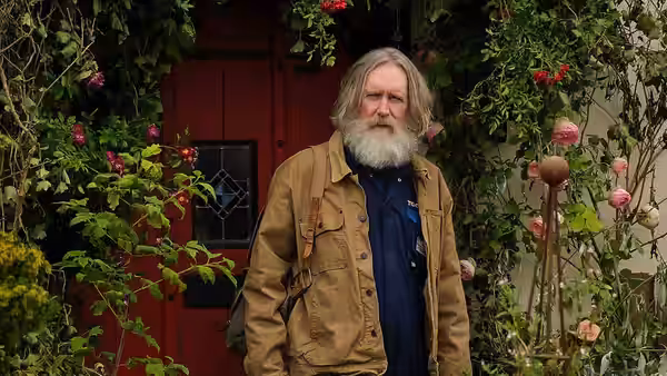 Brian Sleep (Michael Palin) standing before a red door amid flowers