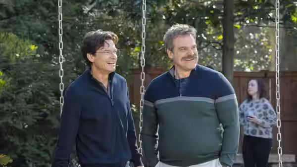 Jason Bateman and David Harbour standing by swings with a woman nearby