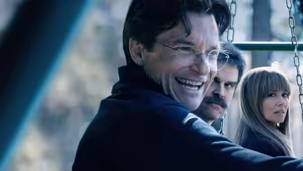 Jason Bateman smiling on a swing with David Harbour and a woman behind