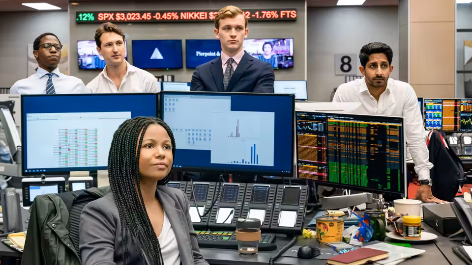 Harper Stern (Myha'la Herrold) at her desk in a busy trading room