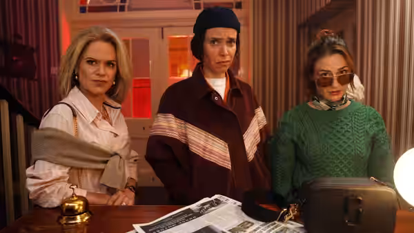 Three women standing together behind a wooden reception counter