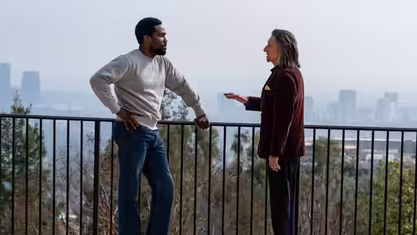 Simon Williams (Yahya Abdul-Mateen II) talking with a man on a balcony