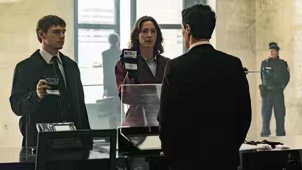 man and woman with badges facing another man in an office lobby