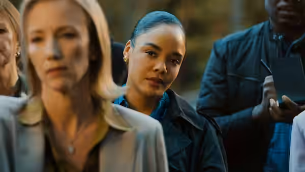 Anna Andrews (Tessa Thompson) standing outdoors among a group of people