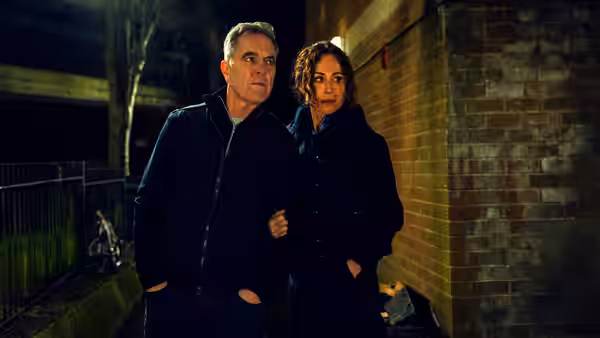 Older man and woman stand together on a street at night