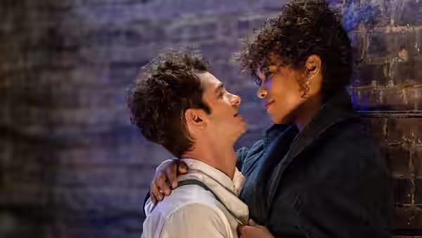 Jonathan Larson (Andrew Garfield) embracing Susan (Alexandra Shipp) against a brick wall