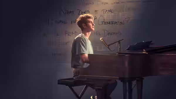 Jonathan Larson (Andrew Garfield) seated at a piano with lyrics on the wall