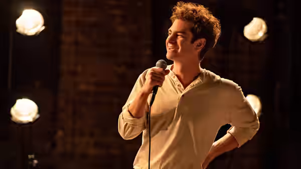 Jonathan Larson (Andrew Garfield) singing into a microphone on a stage