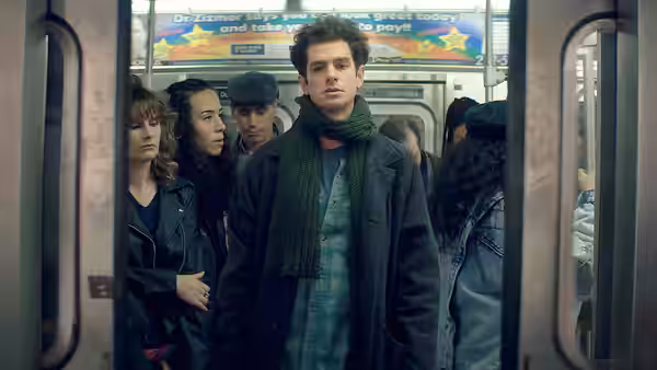 Jonathan Larson (Andrew Garfield) standing in a crowded subway car