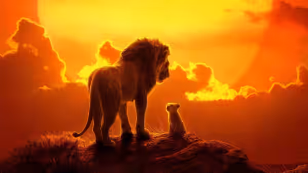 Adult lion and cub stand on a rocky outcrop against a glowing sunset sky